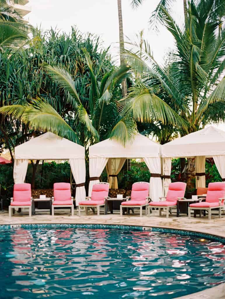 Wellness Retreat Portugal with swimming pool, sun loungers with pink cushions, and white tents underneath the palmtrees