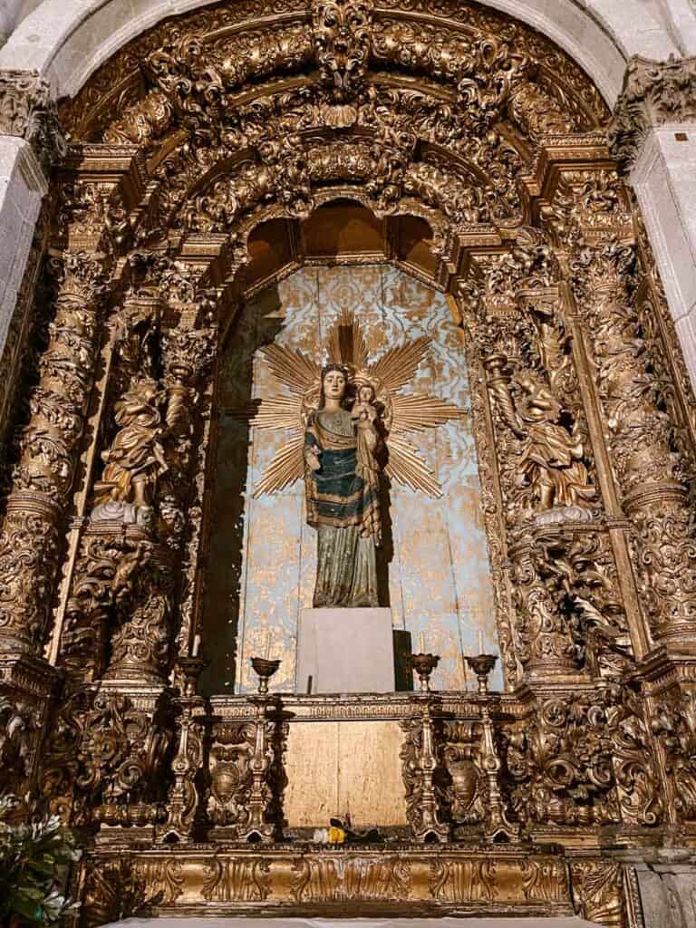 Verguld barok altaarstuk in de Kathedraal in Porto met gedetailleerde houtsnijwerken en een centraal beeld van Maria met kind, omgeven door een stralenkrans en een achtergrond van blauw en goud.