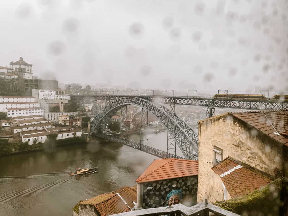 Porto rain drops through a window overlooking the Luís I Bridge