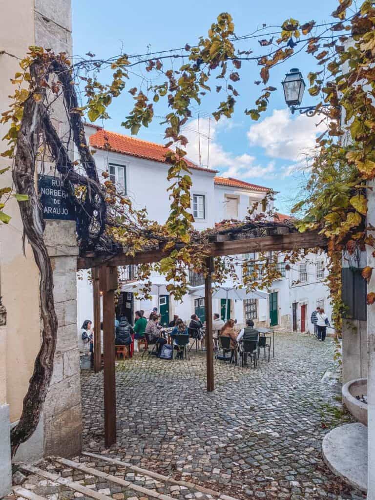 A street in Alfama with people sitting outside during the mild Lisbon temperature January