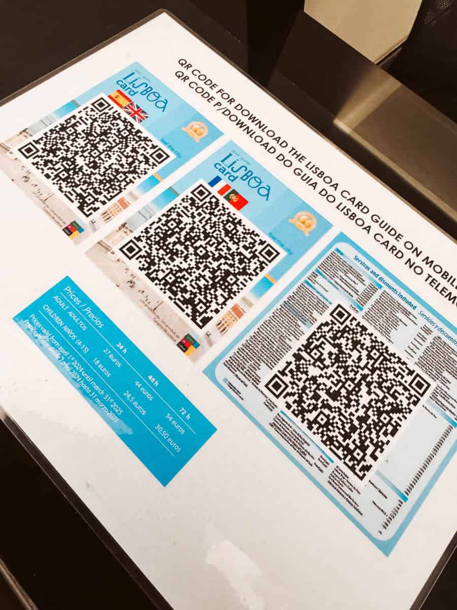 Een afdruk met grote QR-codes ligt op een balie, waarmee reizigers de gids voor de Lisbon Card op hun mobiele telefoon kunnen downloaden. De afbeelding toont verschillende versies van de kaart in meerdere talen, samen met prijsinformatie en inbegrepen kortingen. Dit biedt bezoekers een handige manier om hun stadsbezoek in Lissabon te plannen.