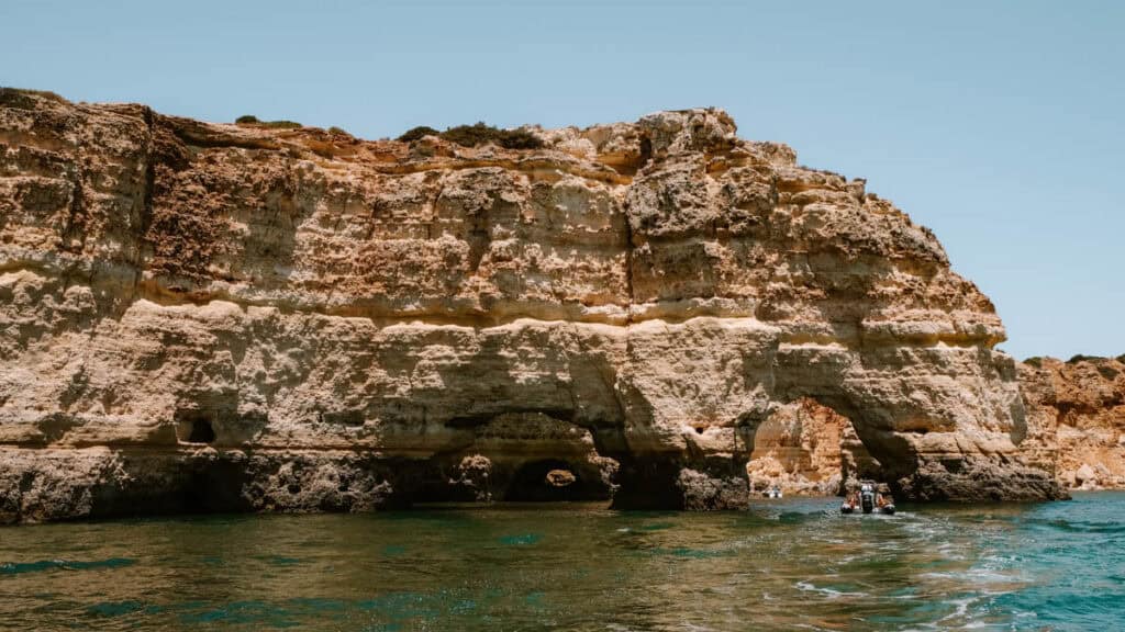 Natuurlijke rotsformaties met bogen aan de kust bij de Benagil grot Algarve, gezien vanaf het water op een heldere zomerdag.
