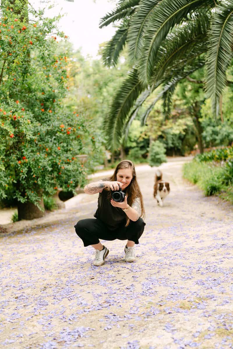 Lissabon fotograaf maakt foto’s in een groen park met palmbomen en paarse bloemblaadjes.