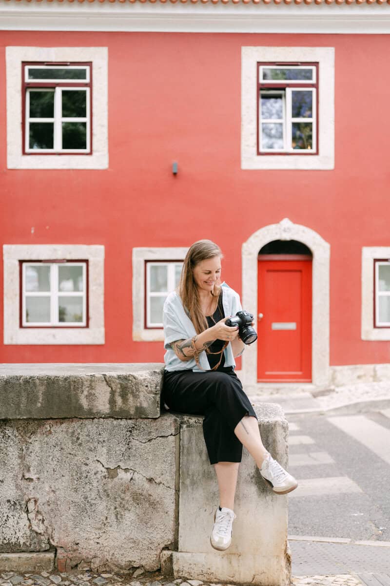 Lissabon fotograaf bekijkt haar camera voor een karakteristiek rood gebouw in de stad.