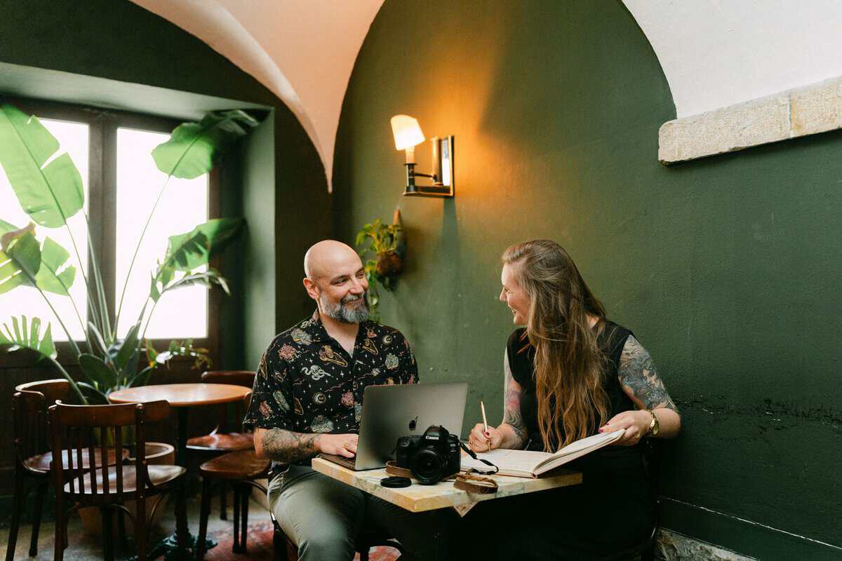 Portugal reisplanning met Discover Portugal aan een tafel met laptop, camera en notitieboek in een sfeervol café.